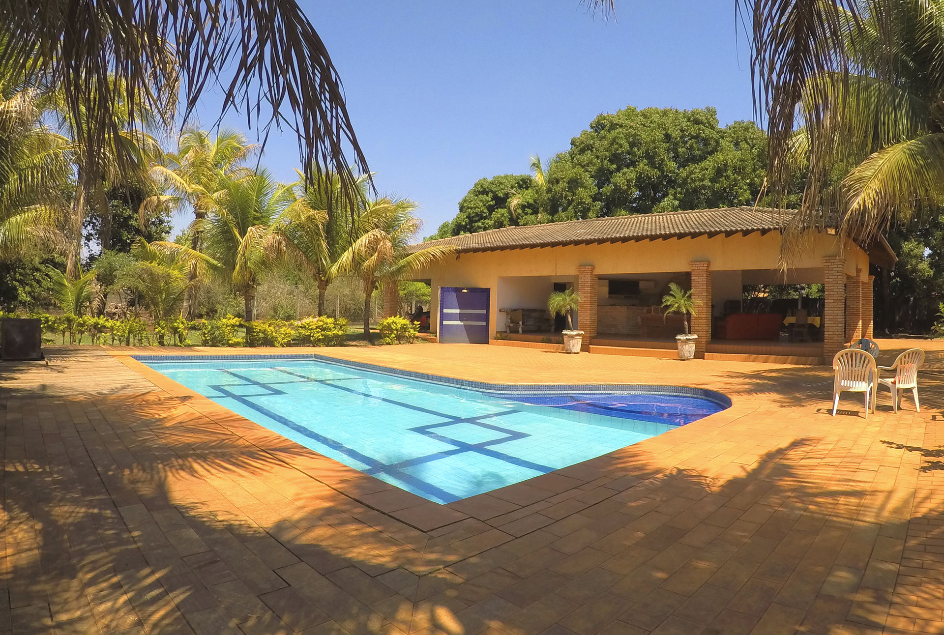 Piscina do Rancho em Cardoso cercada de coqueiros, com a casa ao fundo